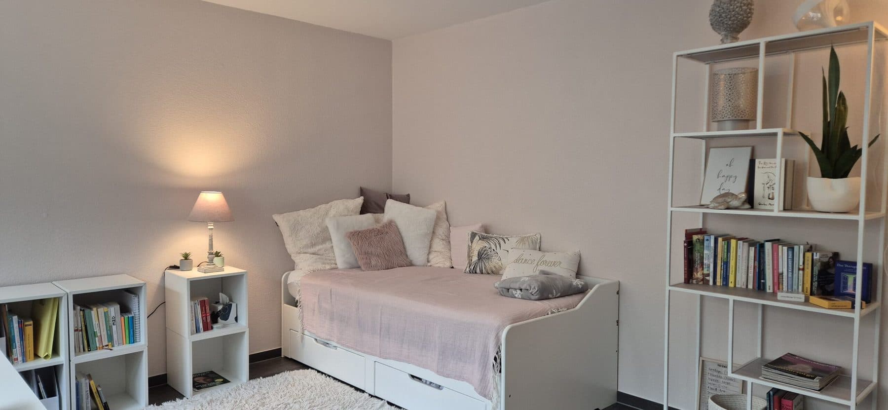 Schlafbereich mit Daybed, Bücherregalen und warmer Tischlampe